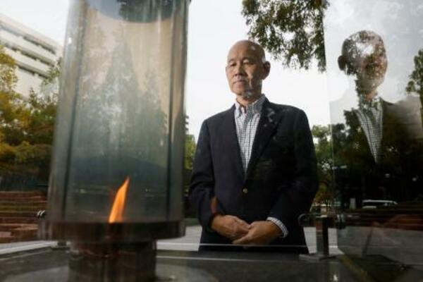 　「１・１７希望の灯り」を見つめる百々孝治さん。阪神大震災で妻子を亡くした＝２０２５年１１月、神戸市中央区の東遊園地