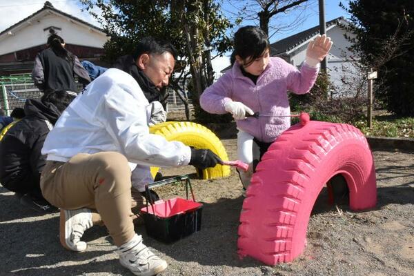 タイヤの遊具にペンキを塗る児童ら