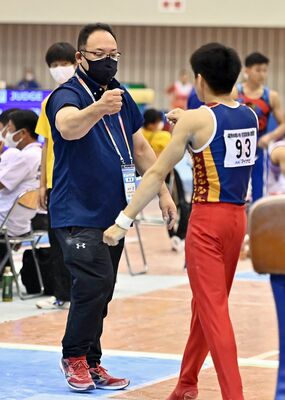 ８月の全国高校総体・体操男子決勝で演技を終えた選手を労う谷田監督（左）＝８月上旬、愛媛県総合運動公園体育館