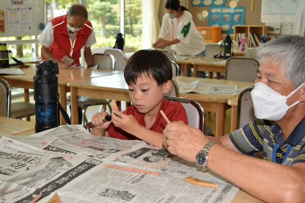 指導を受けながら竹とんぼの羽根を削る子ども