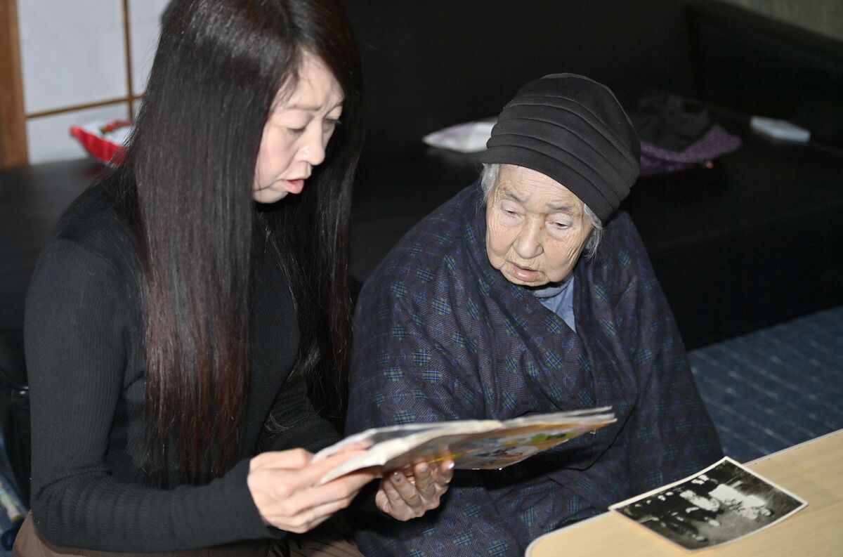 写真を見ながら思い出を振り返る秀美さん（左）とヨシミさんの２人