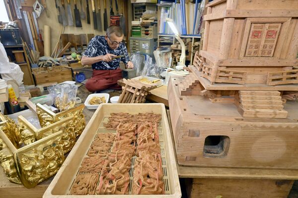 神輿の部品に囲まれ修理作業に打ち込む小川さん＝25日午前10時25分、下野市花の木１丁目