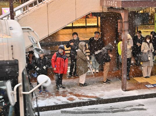 雪が降る中、ＪＲ宇都宮駅西口で列を作ってバスを待つ乗客たち＝５日午後４時40分、宇都宮市駅前通り３丁目