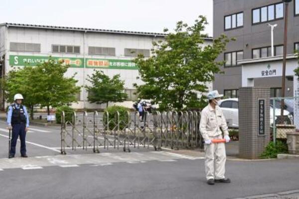 クマに従業員が襲われた「福島製鋼」事業所の入り口付近で警戒する警察官や関係者=2日午前8時54分、福島市