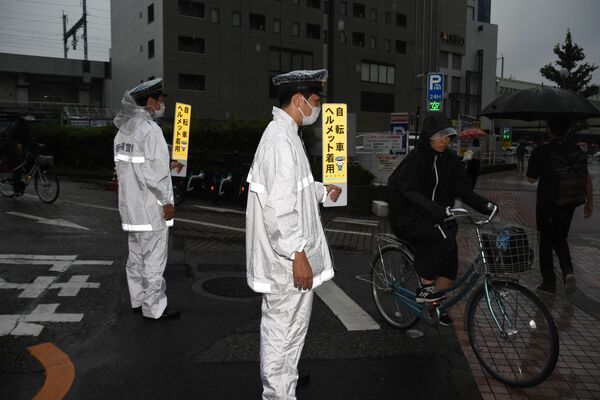 自転車利用者にヘルメットの着用を呼びかける宇都宮東署員＝８日朝、宇都宮市川向町