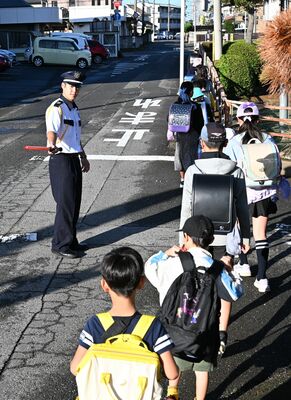 登校する小山市旭小の児童たちの安全を確保する大里さん（左）