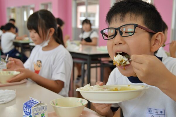 元気に有機野菜カレーを口に運ぶ児童