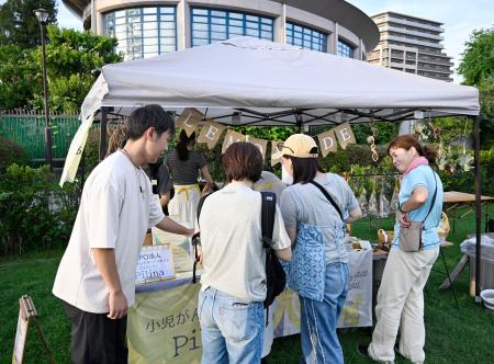 　小児がん患者支援を目的とした活動の趣旨を、訪れた人に説明する土井颯大さん（左端）＝大阪市鶴見区