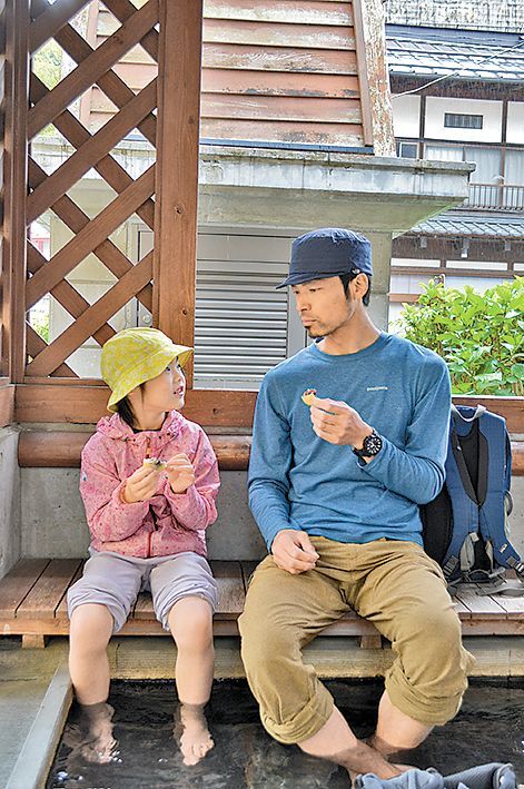 足湯に浸かりながら仲良く温泉まんじゅうを頬張る親子時間
