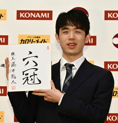 記者会見で「六冠」の直筆色紙を手に笑顔を見せる藤井六冠＝20日午前９時５分、日光きぬ川スパホテル三日月
