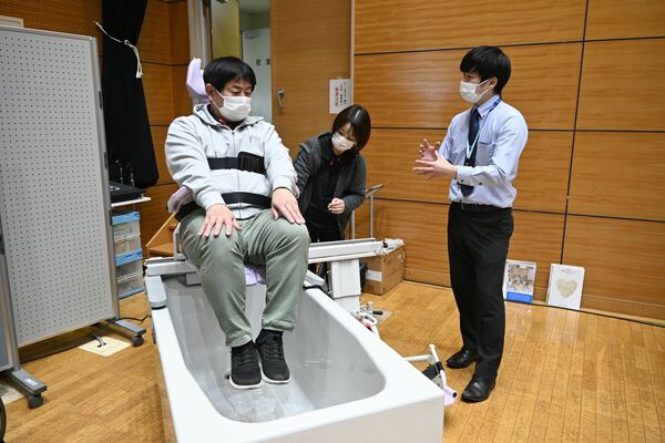 入浴を介助するロボットを試す来場者＝20日午前、宇都宮市若草１丁目