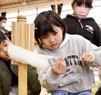 真剣な表情で糸つむぎを体験する児童