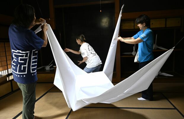 障子紙の巨大折り鶴を飾るメンバーら