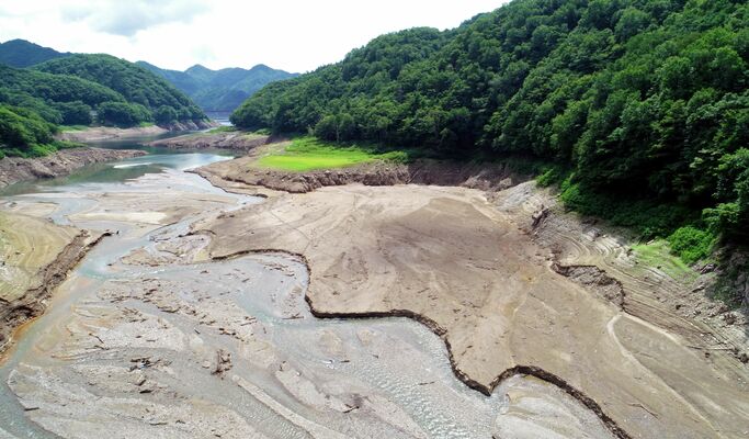 川俣大橋西側の湖底がむき出しになった川俣湖＝26日午前９時55分、日光市川俣、ドローンから