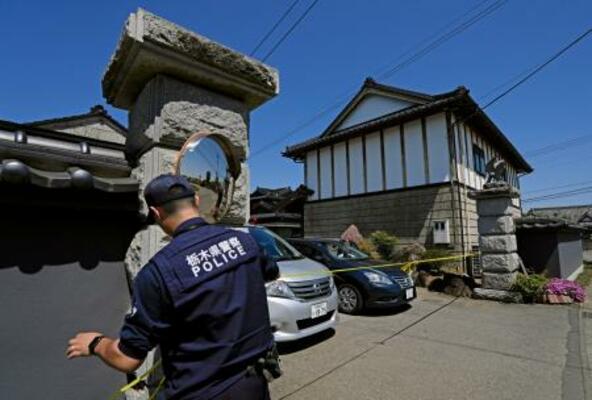 　強盗殺人事件現場の住宅に規制線を張る警察官＝１７日午前９時５２分、栃木県上三川町