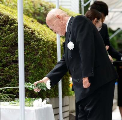 式典で献花する違憲国賠訴訟全国原告団協議会の竪山勲会長=22日午前、厚労省