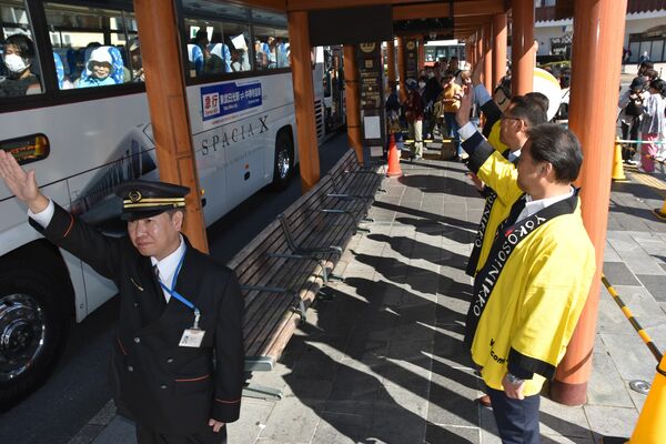 出発する急行バスを見送る粉川市長（右）ら