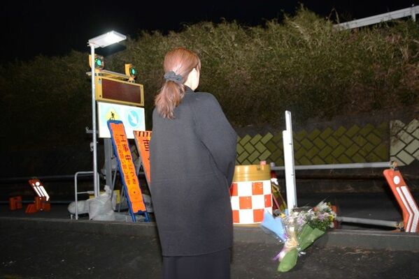 現場近くに花を手向け、事故が起きた新４号国道を見上げる多恵子さん＝14日午後９時20分、宇都宮市下栗町