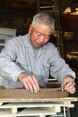 瓦になる前の粘土に模様をつける山上さん