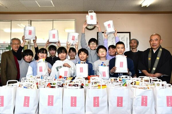 奉納された菓子を受け取った児童と青龍寺住職（右）