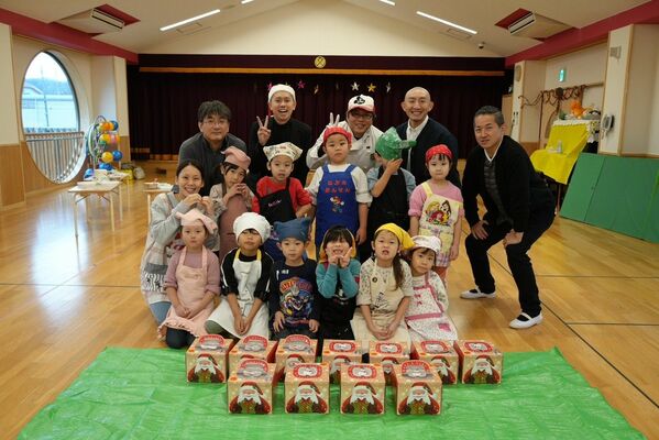 完成したケーキを並べて笑顔を見せる園児や県幼稚園連合会の有志たち＝18日午前、石川県輪島市（同会提供）