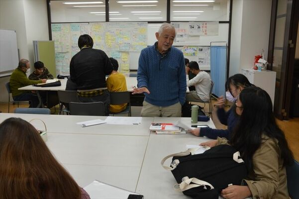 自主夜間中学で外国人の学習者らと談笑する結城代表（中央）