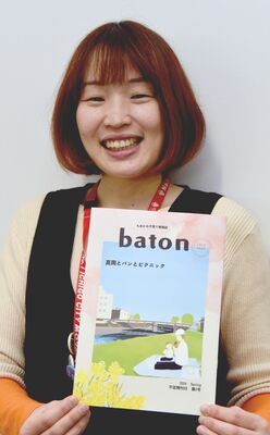 地域情報誌「バトン」を手にする粟村さん