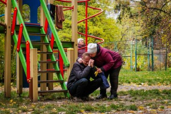ロシアの無人機攻撃で息子を亡くした男性を慰める隣人=26日、ウクライナ・キーウ(AP=共同)