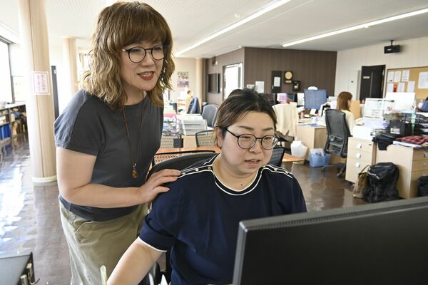 主に事務の業務を担う高橋さん(右)に業務を依頼する深澤社長=18日午前、宇都宮市下川俣町