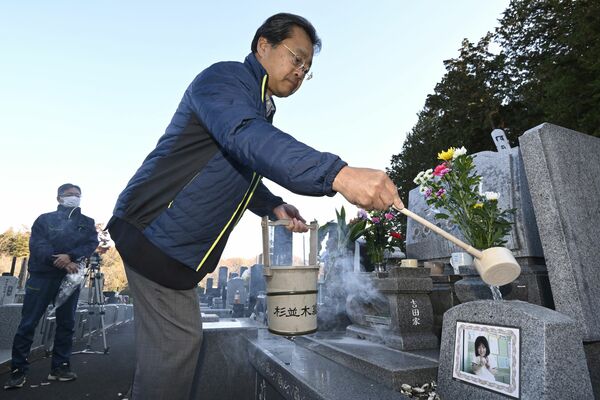 吉田有希さんの墓に水をかける粉川さん＝１日午前９時５分、日光市猪倉（超広角レンズ使用）
