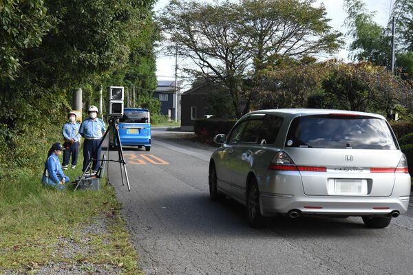 可搬オービスで通行車両の速度違反取り締まりを行う警察官＝29日午前、日光市木和田島（画像は一部加工しています）