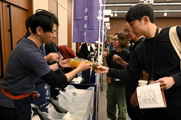 来場者に希望の酒を注ぐ蔵元関係者（左）＝９日午後、東京都内