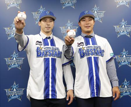 　ソフトバンクから移籍し、記者会見でポーズをとるＤｅＮＡの尾形（左）と井上朋＝１４日、横浜市内の球団事務所