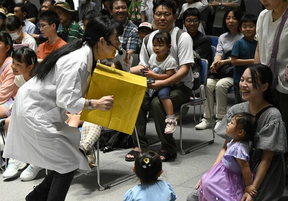 サイエンスショーで空気砲から放たれる空気の流れや勢いを体感する来場者＝15日午前、県議会議事堂