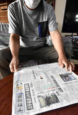 クマによる被害を報じる新聞に目を通す男性＝４日午前、那須塩原市