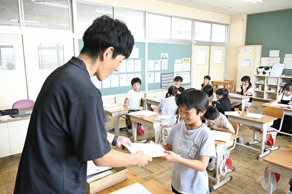 担任教諭から笑顔で通知表を受け取る児童=18日午前10時40分、栃木市都賀町家中、今井心撮影