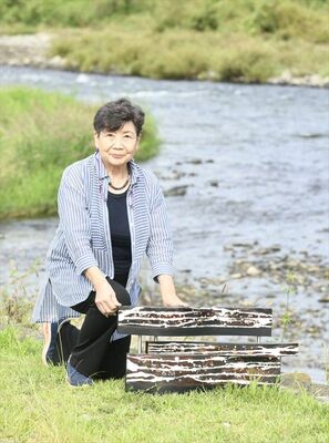 那珂川を前に作品を手にする佐藤さん