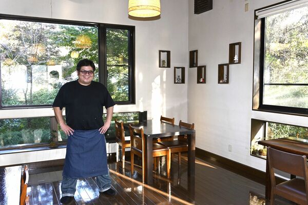 林に囲まれた店内と店長の仲島さん