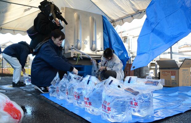 給水タンクから給水袋に水を入れる下野市職員ら＝４日午前９時15分、石橋北小