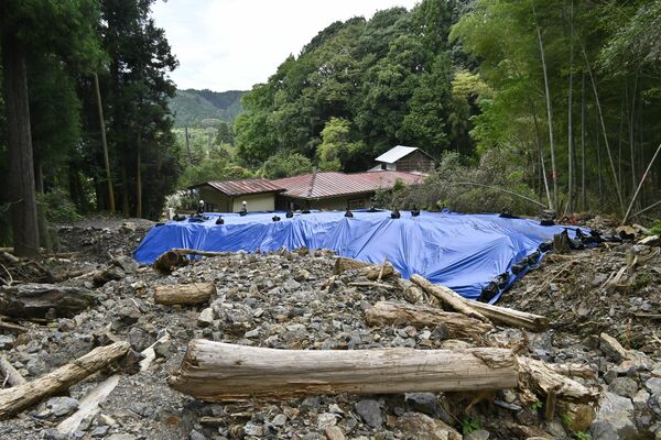土砂崩れに遭った福田さん方（奥）。土砂が流出しないようビニールシートで応急措置されている＝16日午前、鹿沼市引田