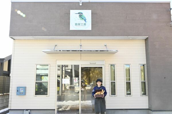 カワセミのロゴが目立つ店の外観と店長の鈴木さん