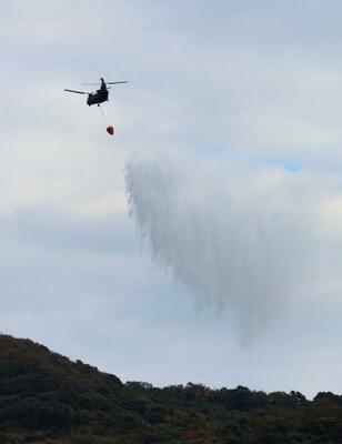 　大分市佐賀関の大規模火災現場付近で上空から散水する自衛隊のヘリコプター＝２０日午前１０時２６分