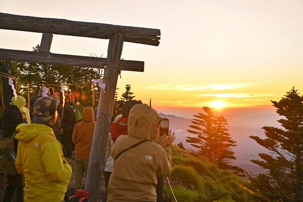 周囲をオレンジ色に染めた御来光に見入る登山客たち＝１日午前４時45分、男体山山頂