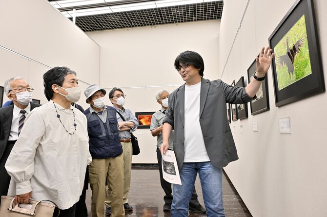 古市さん（右）の作品講評に聞き入る下野写真協会の会員たち＝18日午後、県総合文化センター