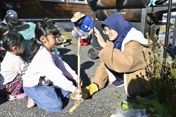 協力しながら火おこしを体験する参加者