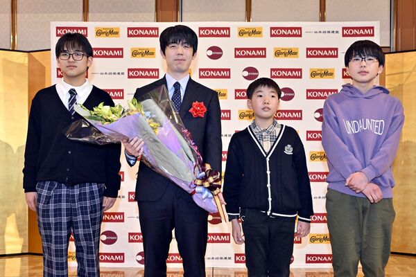 祝賀会で花束を手にほほ笑む藤井棋王（左から２人目）＝15日午後、日光市鬼怒川温泉大原、広瀬華撮影