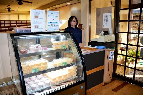 ショーケース内に並ぶプリンと店長の鈴木さん