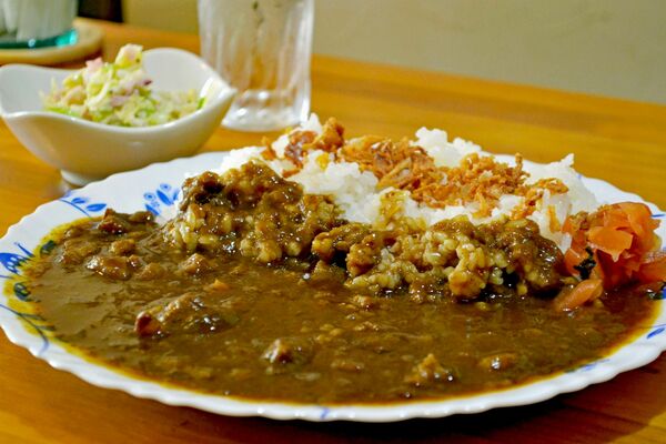 牛スジのコクが味わえる「牛すじカレー」。奥はコールスロー