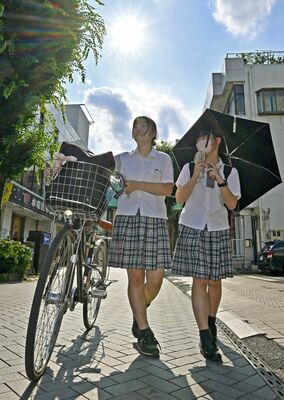 強い日差しの下、日傘を差して下校する高校生＝５日午後３時30分、宇都宮市二荒町