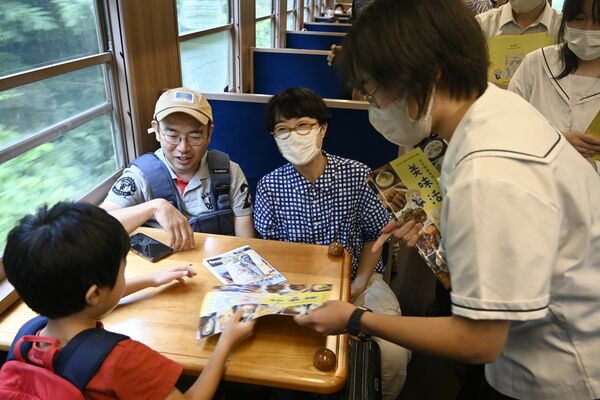 パンフレットを乗客に配る「ぐるめ部」の生徒